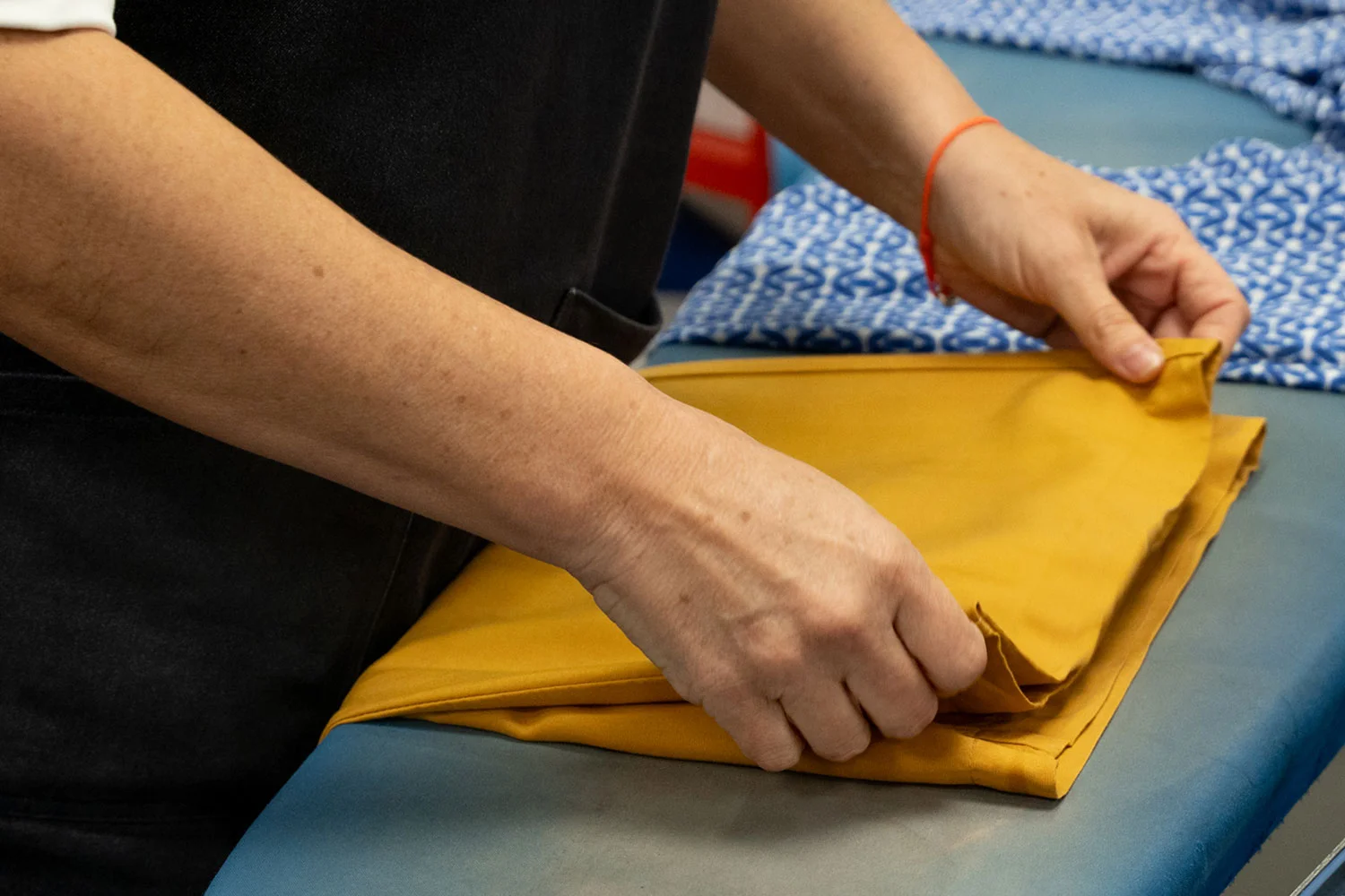 Trained hands folding a recovered garment on the reconditioning bench